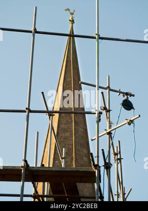 A view of the spire of St Helens Church, Abingdon, partially  obscured by scaffolding on a neighbouring house.   A Christian place of worship has been at this location at the confluence of the Thames and Ock rivers, since the year 995. In fact, a Saxon Minster may have been here since the 7th Century. The Church is named after St Helen, the mother of Emperor Constantine, who made Christianity the official state religion of Rome. It is reputed that she visited the Holy Land in her old age and found fragments of the cross. Here we see the current church and its noted spire from West St Helens St Stock Photo