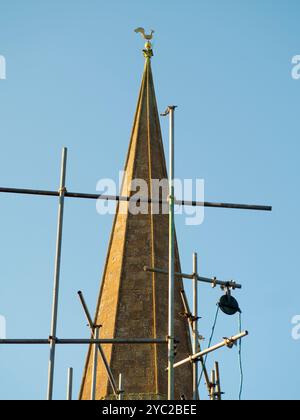 A view of the spire of St Helens Church, Abingdon, partially  obscured by scaffolding on a neighbouring house.   A Christian place of worship has been at this location at the confluence of the Thames and Ock rivers, since the year 995. In fact, a Saxon Minster may have been here since the 7th Century. The Church is named after St Helen, the mother of Emperor Constantine, who made Christianity the official state religion of Rome. It is reputed that she visited the Holy Land in her old age and found fragments of the cross. Here we see the current church and its noted spire from West St Helens St Stock Photo