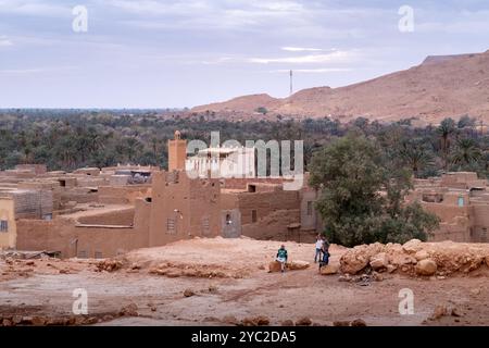 Some children greet the camera in a Small town with mosque into the immense Tafilalet oasis in Morocco, North Africa. Ziz River in the middle of the d Stock Photo