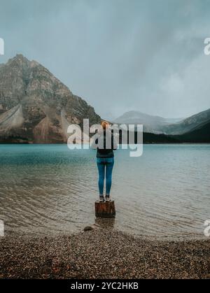 Woman standing on shoreline of Bow Lake in Banff on rainy day. Stock Photo