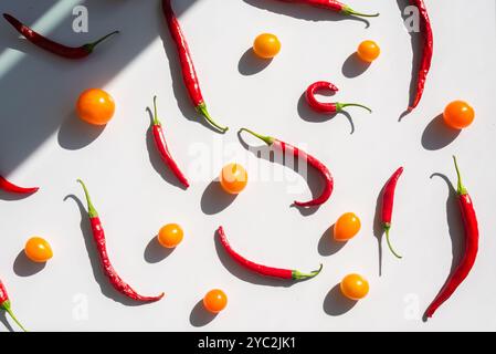 Red chilies and yellow tomatoes scattered on a white background Stock Photo