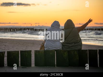Two senior women enjoying an autumn sunset over the sea Stock Photo