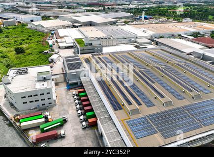 Solar-powered warehouse facility with freight trucks at loading docks. Eco-friendly logistics and efficient cargo transportation. Solar panels Stock Photo