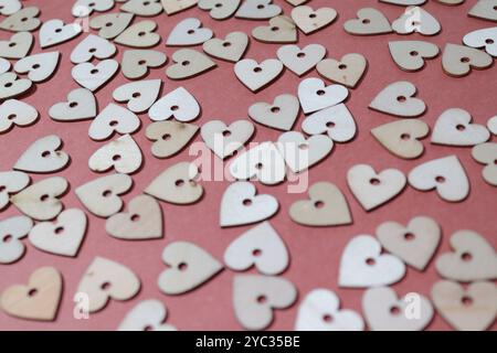 Collection of small wooden hearts against a dark pink background Stock Photo