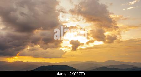 Nature landscape at sunrise with orange sky and soft clouds over peaceful mountain range. Tranquil morning scene. Beauty of dawn and serenity Stock Photo