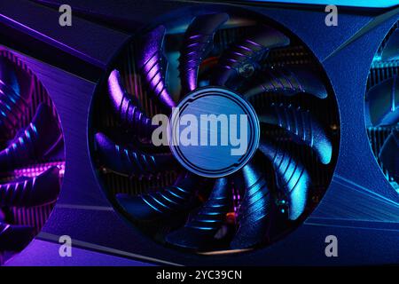 Close-up of high-performance graphics card with cooling fans illuminated by neon lighting. Modern video card for gaming and advanced computing Stock Photo