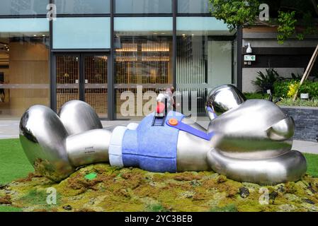 Lying silver bear ornament in the garden area outside a building Stock Photo