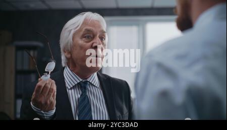 In modern office: Angry boss loses temper, yells at male company employee. Senior team leader and financial specialist having fight over unsuccessful business deal. International corporation or bank. Stock Photo