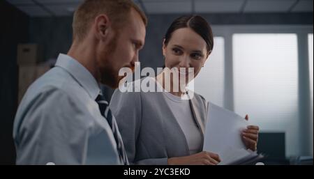 Two office employees working in modern international company: Successful marketing professionals or financial workers analyze documents and projects, discuss investments, brainstorm business strategy. Stock Photo
