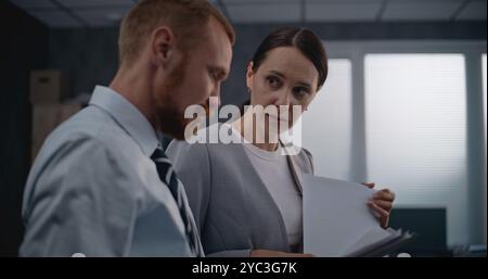 Two office employees working in modern international company: Successful marketing professionals or financial workers analyze documents and projects, discuss investments, brainstorm business strategy. Stock Photo