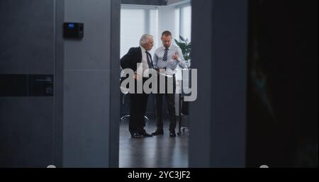 Team leader of department's managers discussing business strategy of company with boss, analyzing papers and documents. Female manager enters meeting room. Business and entrepreneurship concept. Stock Photo