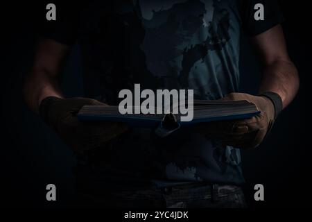 Soldier with an open book in his hands reads on dark background Stock Photo