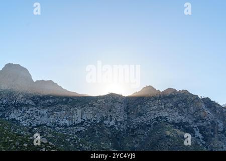 Mountain range in Sequoia with glowing rays of sunlight, casting a warm glow on the top. Stock Photo