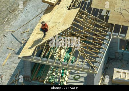 Builders working on roof construction of unfinished residential house with wooden frame structure in Florida suburban area. Housing development concep Stock Photo