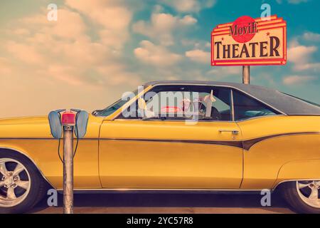 Classic American car parked in a drive-in movie theater with speaker and tray with drinks and food Stock Photo