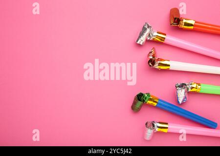 Party foil whistle or noise maker horn rolled on pink background. Top view Stock Photo