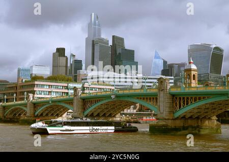 Uber Boat by Thames Clippers passing under Southwark Bridge on River Thames with a backdrop of the City of London skyline Stock Photo