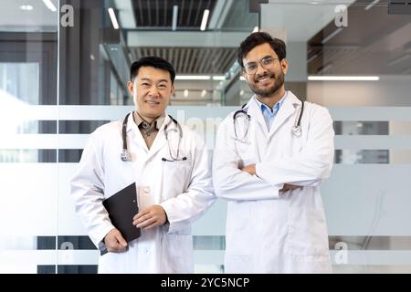 Two smiling doctors in lab coats stand confidently, representing professionalism and teamwork in medical facility. Keywords: doctors, healthcare, team Stock Photo