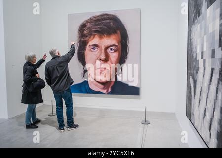 An older couple discussing a painting on a white wall inside a spacious art gallery. Stock Photo