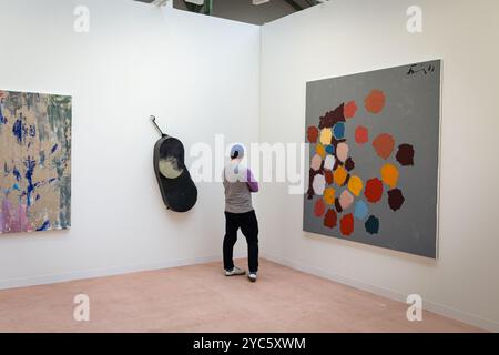 Paris, France. 18th Oct, 2024. A man looks at works of art from one of the galleries taking part in the Art Basel contemporary art fair at the Grand Palais in Paris. The third edition of Art Basel Paris, the contemporary art fair, has finally moved to the Grand Palais, after three years of restoration work on the historic Parisian building. The event takes place between 18 and 20 October and features 195 galleries from 42 countries. Credit: SOPA Images Limited/Alamy Live News Stock Photo