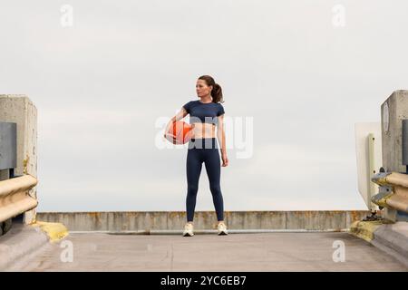 Sporty woman holding a basketball under her arm, outdoors. Stock Photo