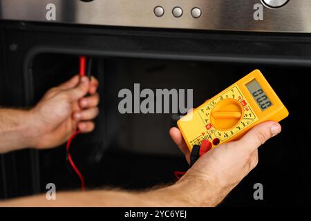 Repairman testing oven element with multimeter, closeup Stock Photo