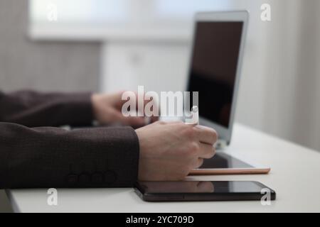 Businessman using different devices at white table indoors, closeup. Modern technology Stock Photo