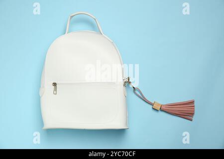 Backpack with pink leather keychain on light blue background, top view Stock Photo
