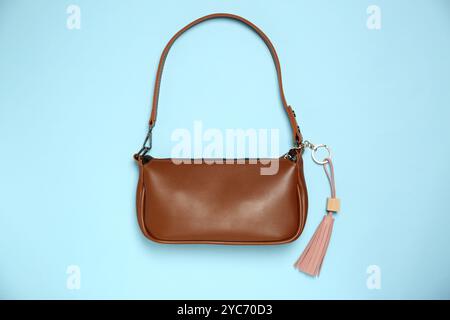 Bag with pink leather keychain on light blue background, top view Stock Photo