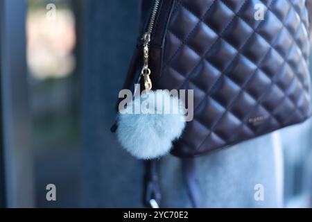 Woman with faux fur keychain on her backpack outdoors, closeup. Selective focus Stock Photo