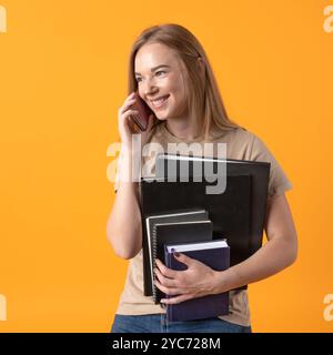 Lifestyle, technology, telecommunications, business and occupation concept. A smiling young woman talking on the phone while holding folders and noteb Stock Photo