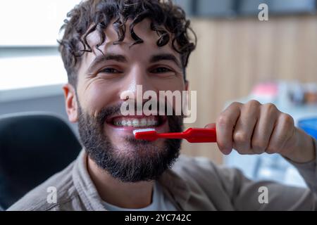 daily dental care and oral hygiene. Man with beard in dentist’s office holding toothbrush Stock Photo