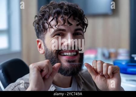 Man holding dental floss following hygiene routine to maintain fresh and healthy teeth and braces Stock Photo