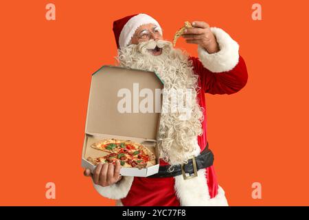 Santa Claus eating tasty pizza on orange background Stock Photo