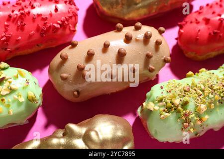 Composition with tasty glazed eclairs on pink background, closeup Stock Photo