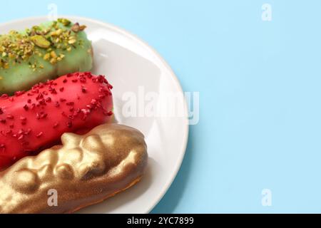 Plate with tasty glazed eclairs on color background Stock Photo