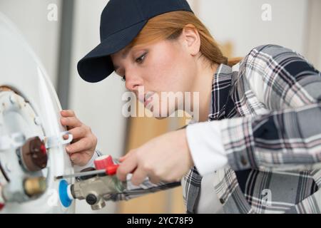 young female plumber working on water heater Stock Photo