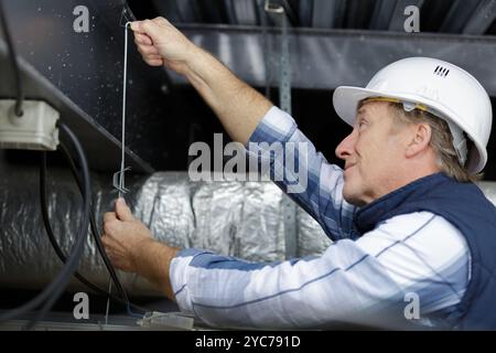 specialist at work repair ventilation system in ceiling Stock Photo