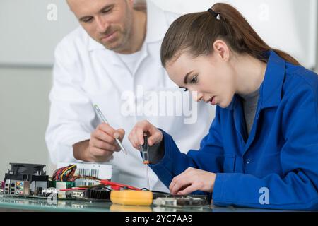 supervisor watching over electronics students at work Stock Photo