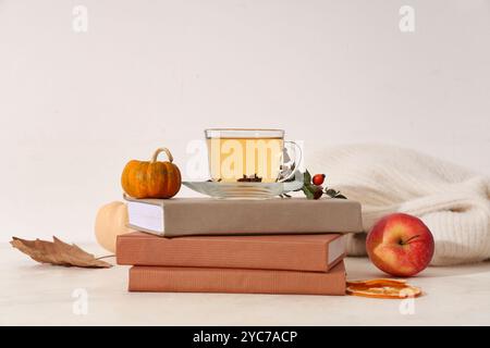 Composition with stack of notebooks, cup of green tea and sweater on table near light wall Stock Photo
