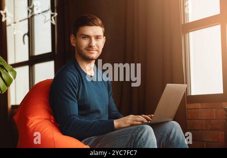 Guy Working On Laptop Looking At Camera In Coworking Workspace Stock Photo
