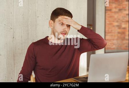 Overworked Employee Looking At Laptop In Shock Sitting In Office Stock Photo