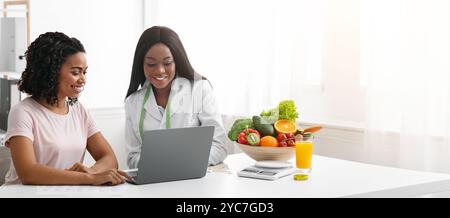 Smiling female doctor and patient using laptop in clinic Stock Photo