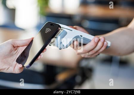 Close Up of a Customer Making a Secure Contactless Online Payment Using a Smartphone with a Credit Card Banking NFC App. Modern Shopper Buying Organic Stock Photo
