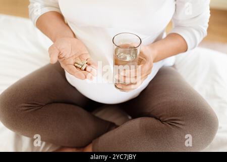 Pregnant woman taking vitamins with a glass of water at home Stock Photo