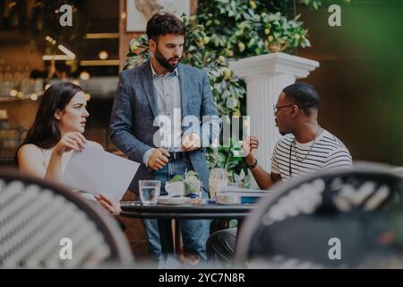 A diverse group of business professionals brainstorms and strategizes during a meeting in a stylish coffee shop. Stock Photo