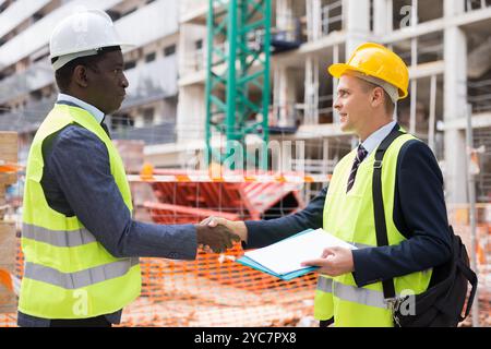 Two engineers concluding agreement and shaking hands Stock Photo