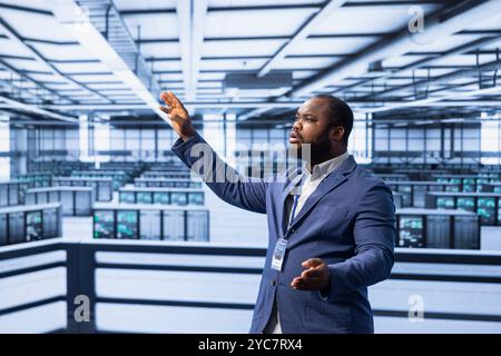 Engineer in data center implementing backup solutions to protect against data loss using AR hologram visualization. Server room worker resolving technical issues using augmented reality technology Stock Photo