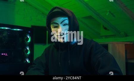 Lviv, Ukraine - June 03, 2024: Man in mask using mobile phone smartphone anonymous looking at camera technology program secure stealing danger banking Stock Photo