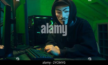 Lviv, Ukraine - June 03, 2024: Man hacker anonymous attack bank criminal typing computer keyboard network cyberspace virus danger technology Stock Photo